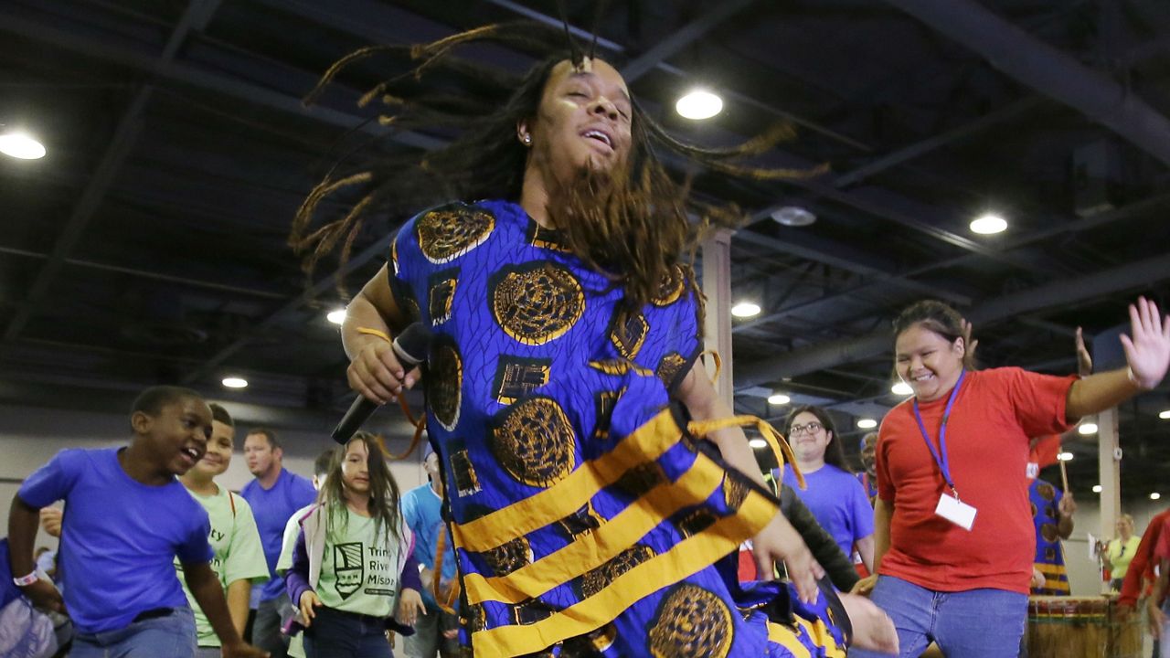 FILE - T.J. with the Bandan Koro African Dance Ensemble leads children dancing during a Juneteenth celebration at Fair Park in Dallas, Monday, June 19, 2017. (AP Photo/LM Otero)