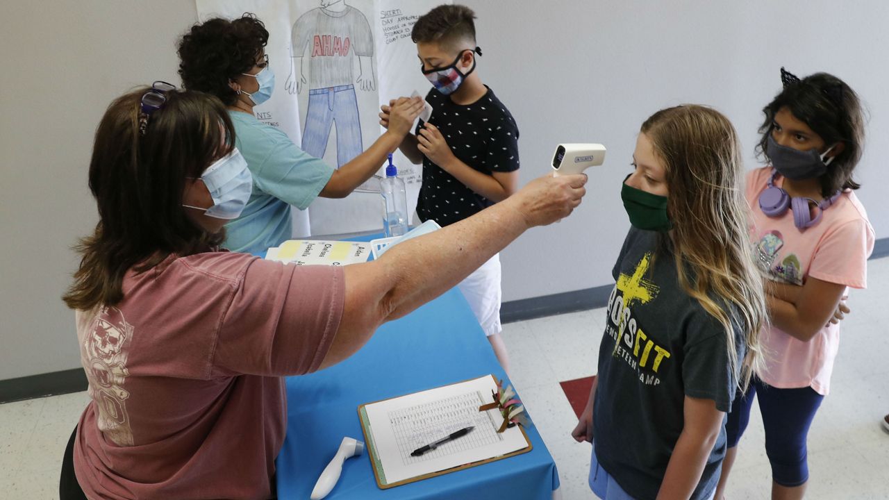 FILE - In this Tuesday, July 14, 2020 file photo, Amid concerns of the spread of COVID-19, science teachers Ann Darby, left, and Rosa Herrera check-in students before a summer STEM camp at Wylie High School in Wylie, Texas. (AP Photo/LM Otero, File)