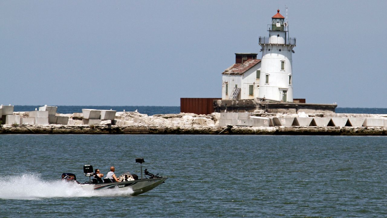Two fishermen in a bass boat speed past the harbor lighthouse in Cleveland. (AP Photo/Mark Duncan)