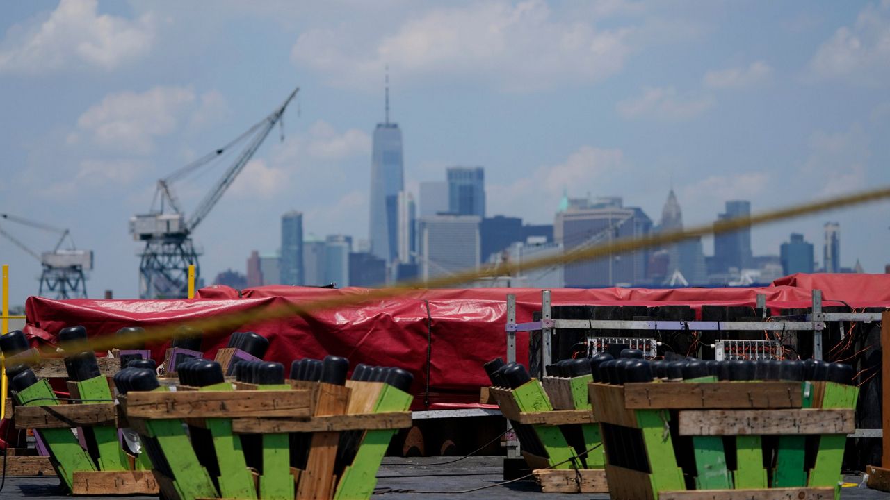 The Manhattan skyline is seen behind a barge filled with fireworks in the Brooklyn borough of New York, Tuesday, June 29, 2021. More than 65,000 shells will be launched from five barges on the East River as part of the Macy's Fourth of July fireworks show on Sunday. (AP Photo/Seth Wenig)