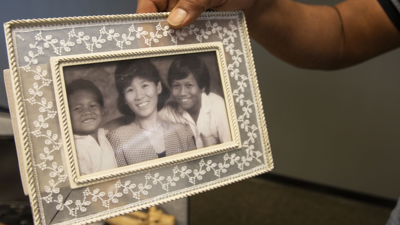 Robert Peterson holds a photo showing his late mother, Yong Ae Yue, on Thursday, March 10, 2022, in Atlanta. Yue was one of eight people shot and killed at various massage businesses on March 16, 2021. (AP Photo/Ron Harris)