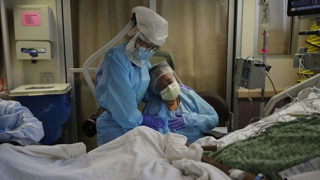 FILE - In this July 31, 2020, file photo, Romelia Navarro, right, is comforted by nurse Michele Younkin, left, as she weeps while sitting at the bedside of her dying husband, Antonio Navarro, in St. Jude Medical Center's COVID-19 unit in Fullerton, Calif. Antonio was Younkin's first COVID-19 patient to pass on her watch. (AP Photo/Jae C. Hong, File)