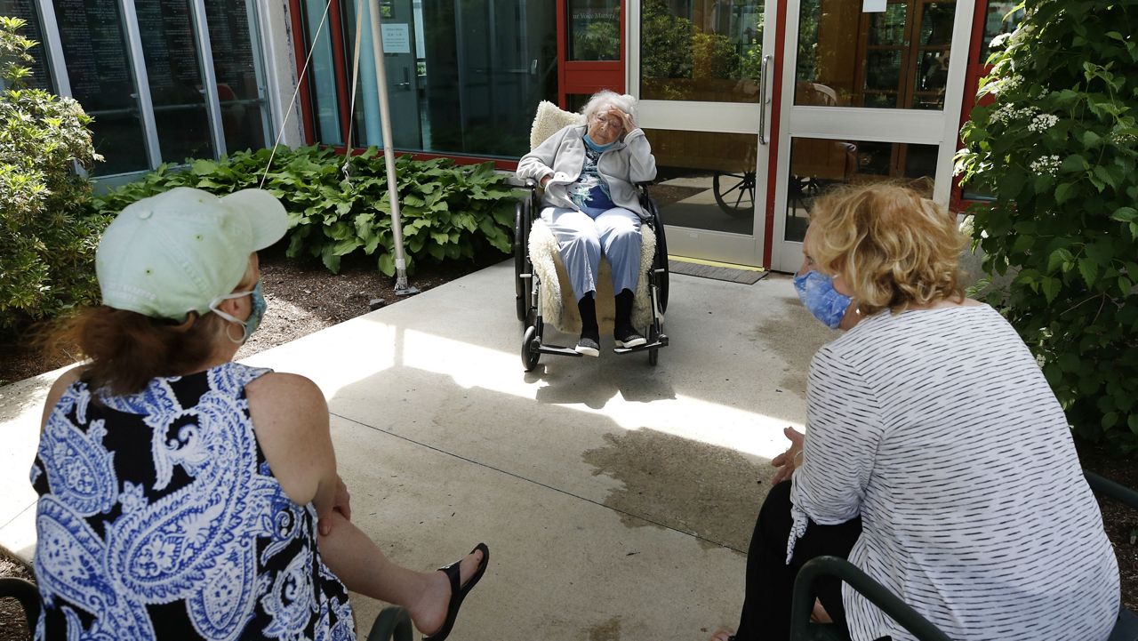 Eva Davis, 94, middle, speaks with her daughters Lori Hall, left, and Elaine Krohn, right, outdoors at the Hebrew Rehabilitation Center, Wednesday June 10, 2020, in Boston, under the state's new nursing home visitation guidelines which requires social distancing. The women hadn't been able to visit in person since March. (AP Photo/Elise Amendola)