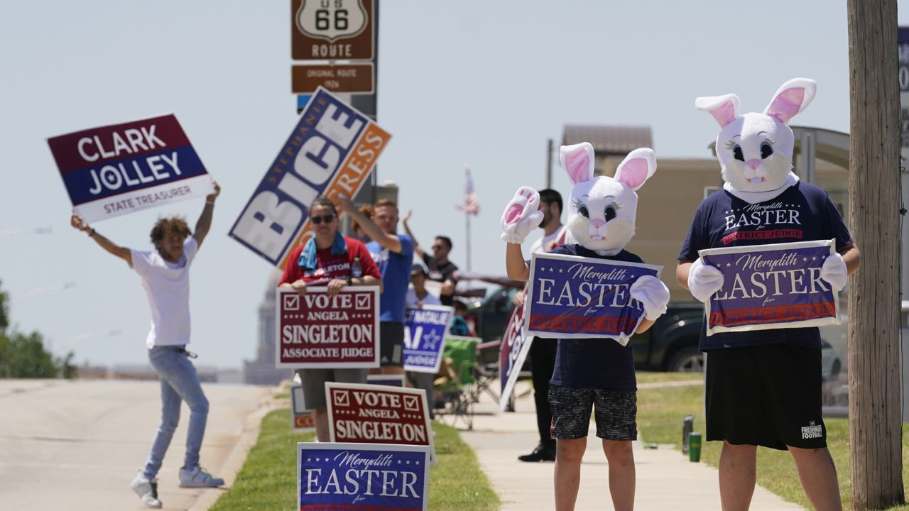 Campaign workers hold signs outside an early voting location Thursday, June 23, 2022, in Oklahoma City. (AP Photo/Sue Ogrocki)