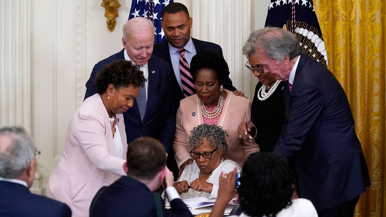 People take photos as Opal Lee holds a pen and is seated where President Joe Biden signed the Juneteenth National Independence Day Act, in the East Room of the White House, Thursday, June 17, 2021, in Washington. (AP Photo/Evan Vucci)