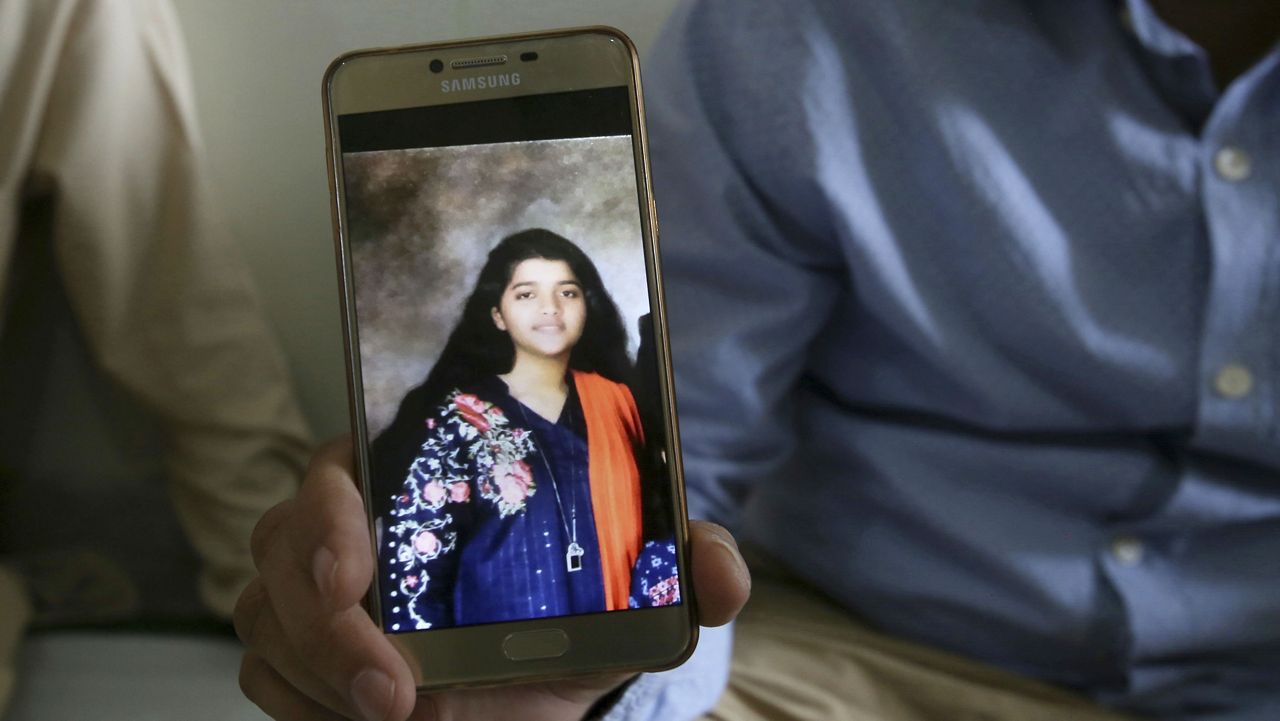 Abdul Aziz Sheikh, center, father of Sabika Sheikh, a victim of a shooting at a Texas high school, shows a picture of his daughter in Karachi, Pakistan, Saturday, May 19, 2018. (AP Photo/Fareed Khan)