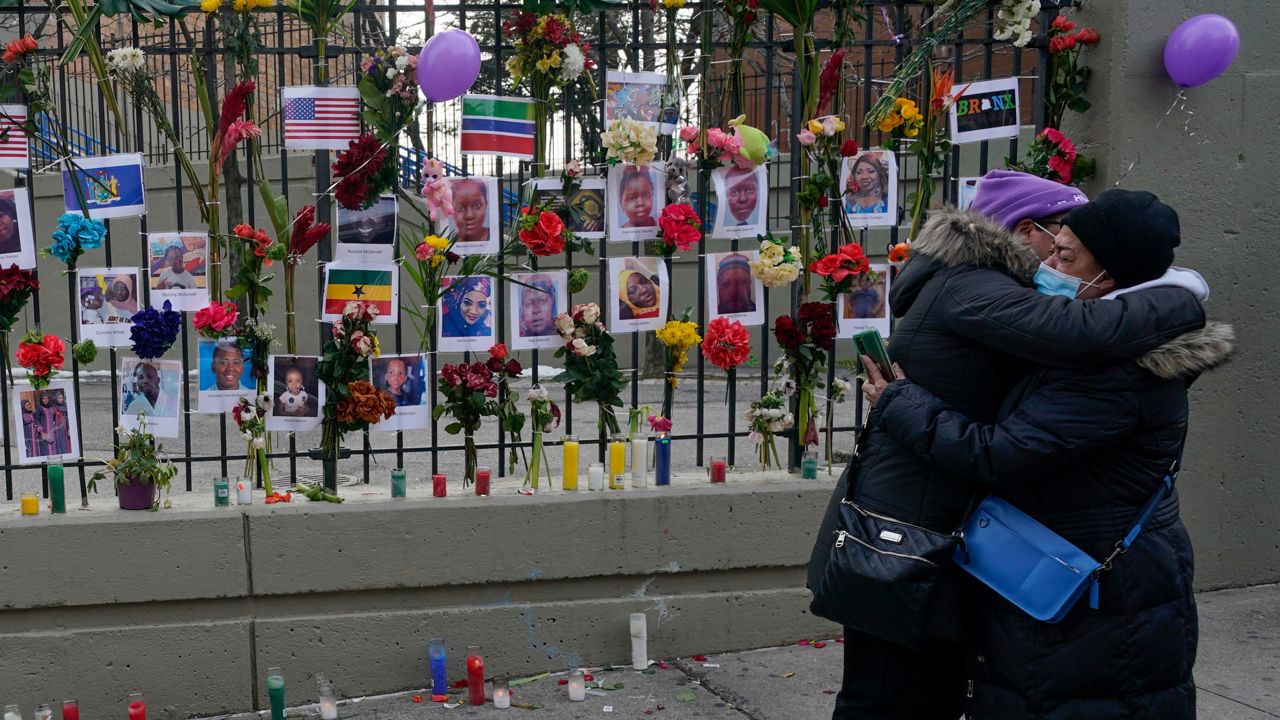 People hug after viewing a memorial for the victims of an apartment building fire near the site of the fire in the Bronx borough of New York, Thursday, Jan. 13, 2022. (AP Photo/Seth Wenig)