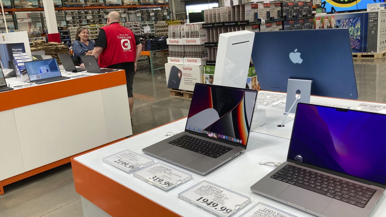 A sales associate helps a prospective customer as laptops sit on display in a Costco warehouse Monday, Aug. 15, 2022, in Sheridn, Colo. (AP Photo/David Zalubowski)