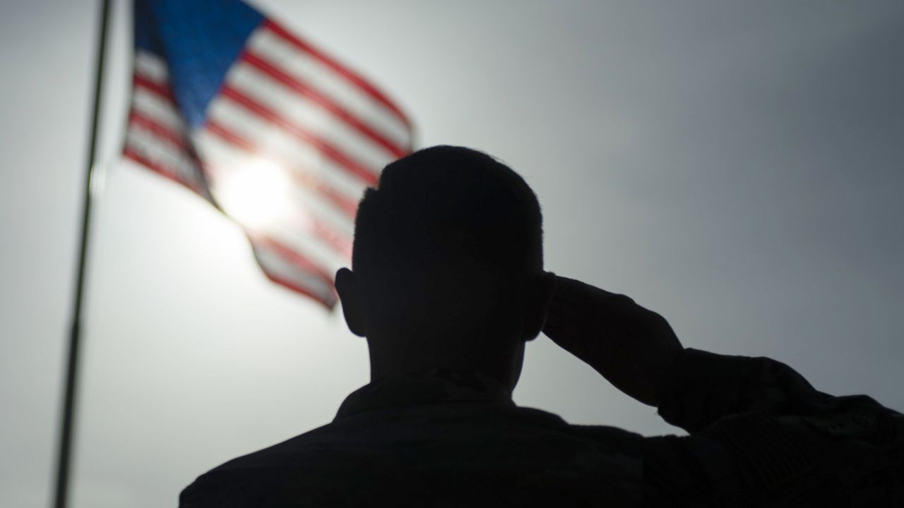 FILE - In this photo taken Aug. 26, 2019 and released by the U.S. Air Force, a U.S. Air Force Staff Sgt., salutes the flag during a ceremony signifying the change from tactical to enduring operations at Camp Simba, Manda Bay, Kenya. (Staff Sgt. Lexie West/U.S. Air Force via AP, File )