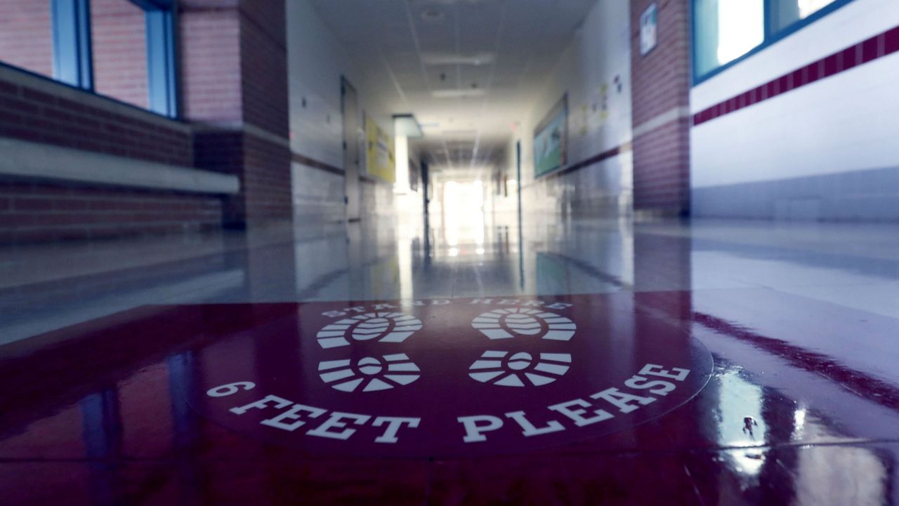 A social distancing reminder sits on the floor of an empty hallway at Stephens Elementary School in Rowlett, Texas, Wednesday, July 22, 2020. (AP Photo/LM Otero)