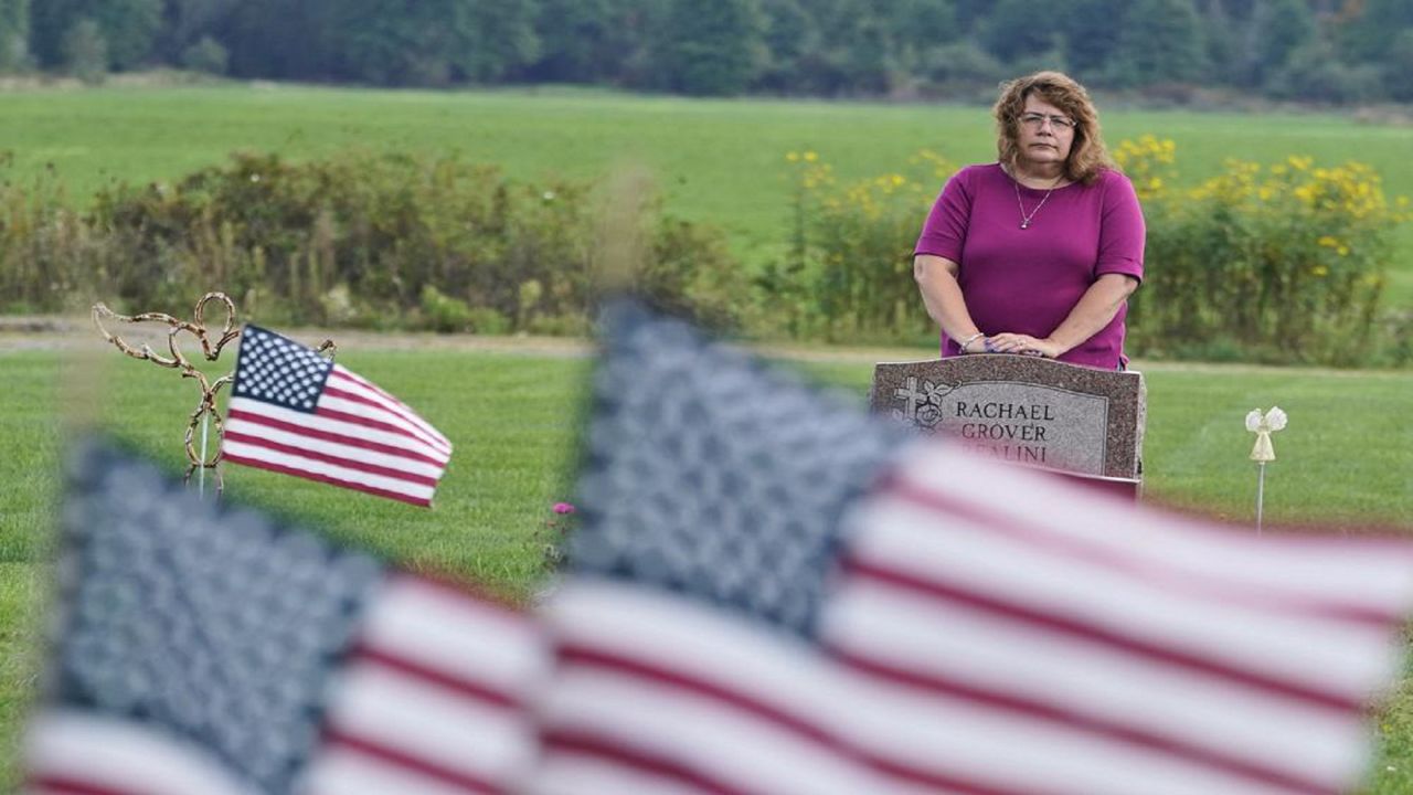 Sharon Grover stands over the grave of her daughter, Rachael, Tuesday, Sept. 28, 2021, at Fairview Cemetery in Mesopotamia, Ohio. Grover believes her daughter started using prescription painkillers around 2013 but missed any signs of her addiction as her daughter, the oldest of five children, remained distanced. (AP Photo/Tony Dejak)