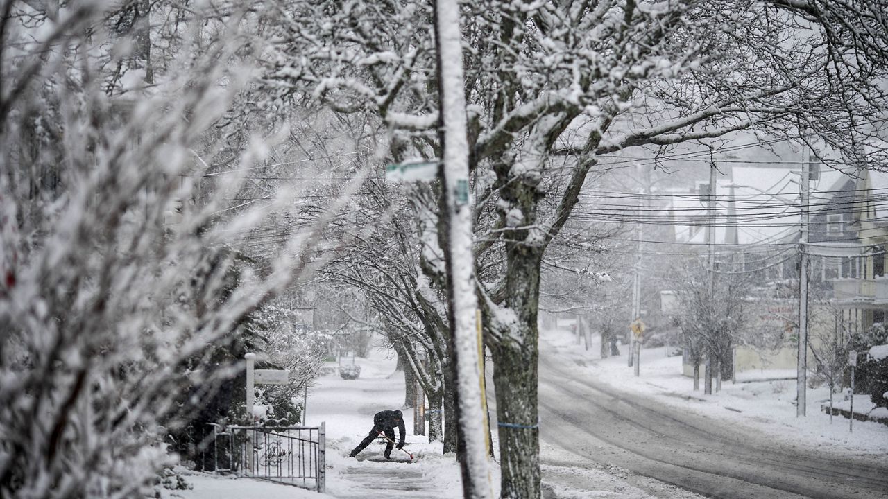 A worker shovels snow off a sidewalk Tuesday, Feb. 13, 2024, in Providence, R.I. (AP Photo/David Goldman)