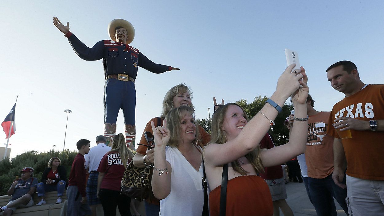 FILE - Fans gather for a photo in front of Big Tex at the state fair before an NCAA college football game between Texas and Oklahoma in Dallas Saturday, Oct. 10, 2015. (AP Photo/LM Otero)