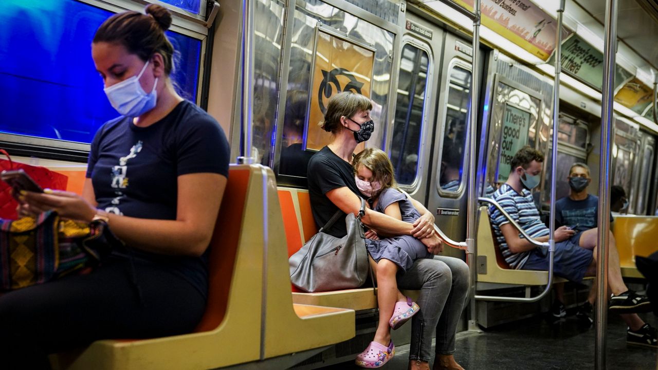 In this Aug. 17, 2020, file photo, New York City subway passengers wear protective masks due to COVID-19 concerns. Motorists and mass transit riders in New York already facing fare and toll increases next year and in 2023 could face drastic service cuts if the federal government doesn't help the Metropolitan Transportation Authority out of a gaping budget hole brought on by the COVID-19 pandemic, according to a state comptroller's report released Tuesday, Oct. 13, 2020. (AP Photo/John Minchillo, File)
