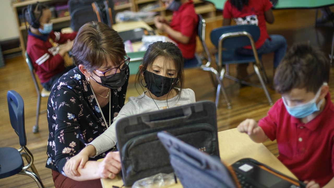 A Kindergarten teacher works with a student at Raices Dual Language Academy, a public school in Central Falls, R.I., Feb. 9, 2022. (AP Photo/David Goldman, File)