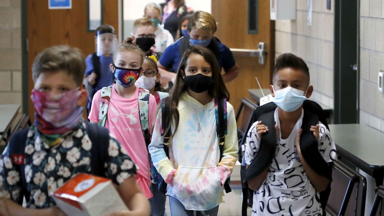 Wearing masks to prevent the spread of COVID19, elementary school students walk to classes to begin their school day in Godley, Texas, Wednesday, Aug. 5, 2020. (AP Photo/LM Otero)