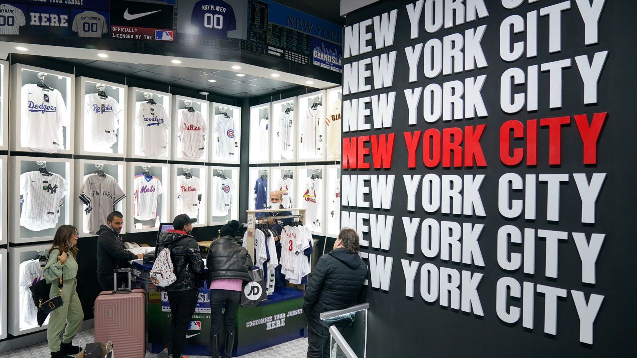 People shop at Grand Slam, a souvenir and sports apparel store, in Times Square, Monday, Nov. 15, 2021, in New York. Even as visitors again crowd below the jumbo screens in New York’s Times Square, the souvenir shops, restaurants, hotels and entrepreneurs within the iconic U.S. landmark are still reeling from a staggering pandemic. (AP Photo/Seth Wenig)