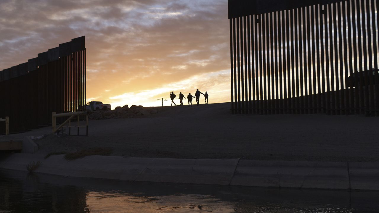 In this Thursday, June 10, 2021, file photo, a pair of migrant families from Brazil pass through a gap in the border wall to reach the United States after crossing from Mexico to Yuma, Ariz., to seek asylum. (AP Photo/Eugene Garcia, File)