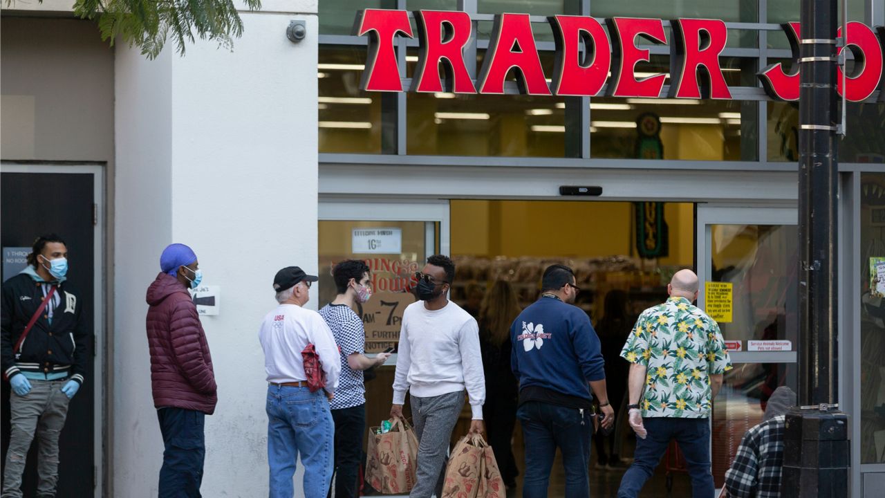 People stand in line, but leaving space to the neighboring person, while waiting to enter a Trader Joe's grocery store in the Hollywood section of Los Angeles on Tuesday, March 24, 2020. (AP Photo/Damian Dovarganes)