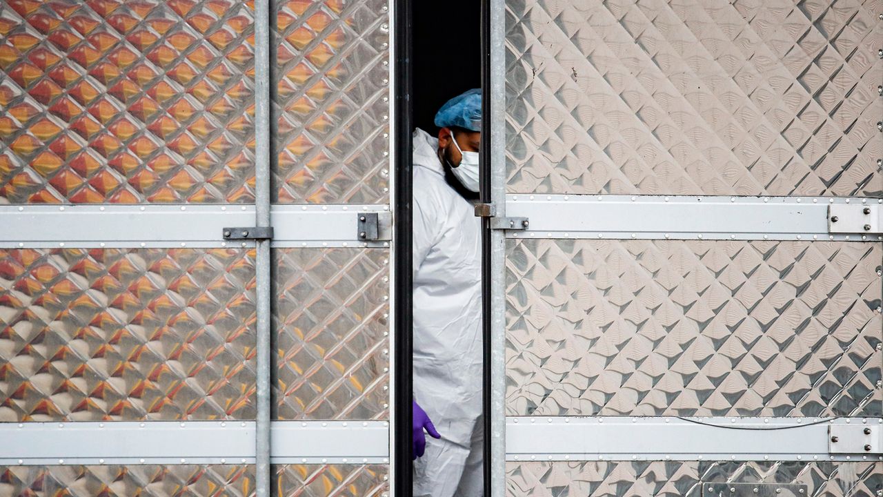 A person in PPE stands inside a mobile morgue truck. (AP Image/File)
