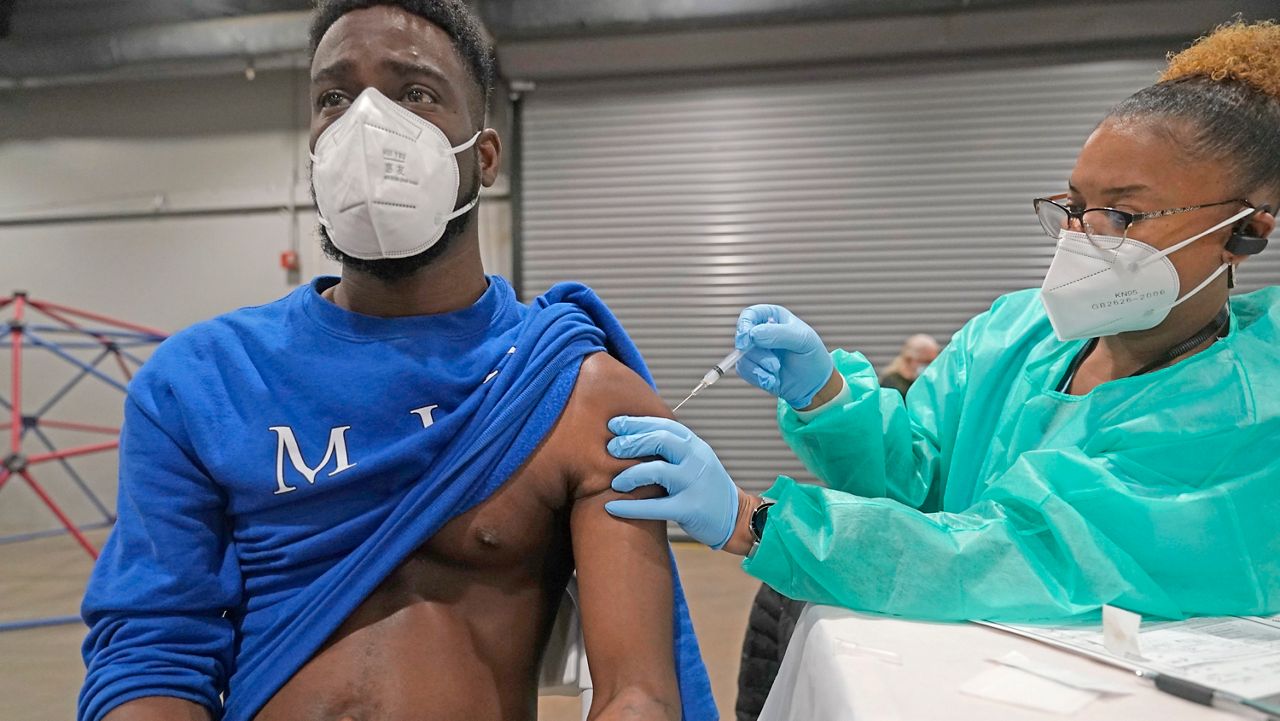 Dominick Taylor, left, receives his second dose of the COVID-19 vaccine from Lesia Turner at the Dallas County mass vaccination site at Fair Park Wednesday, Jan. 20, 2021, in Dallas. Taylor is a front line worker with Dallas County Human and Health Resources. (AP Photo/LM Otero)