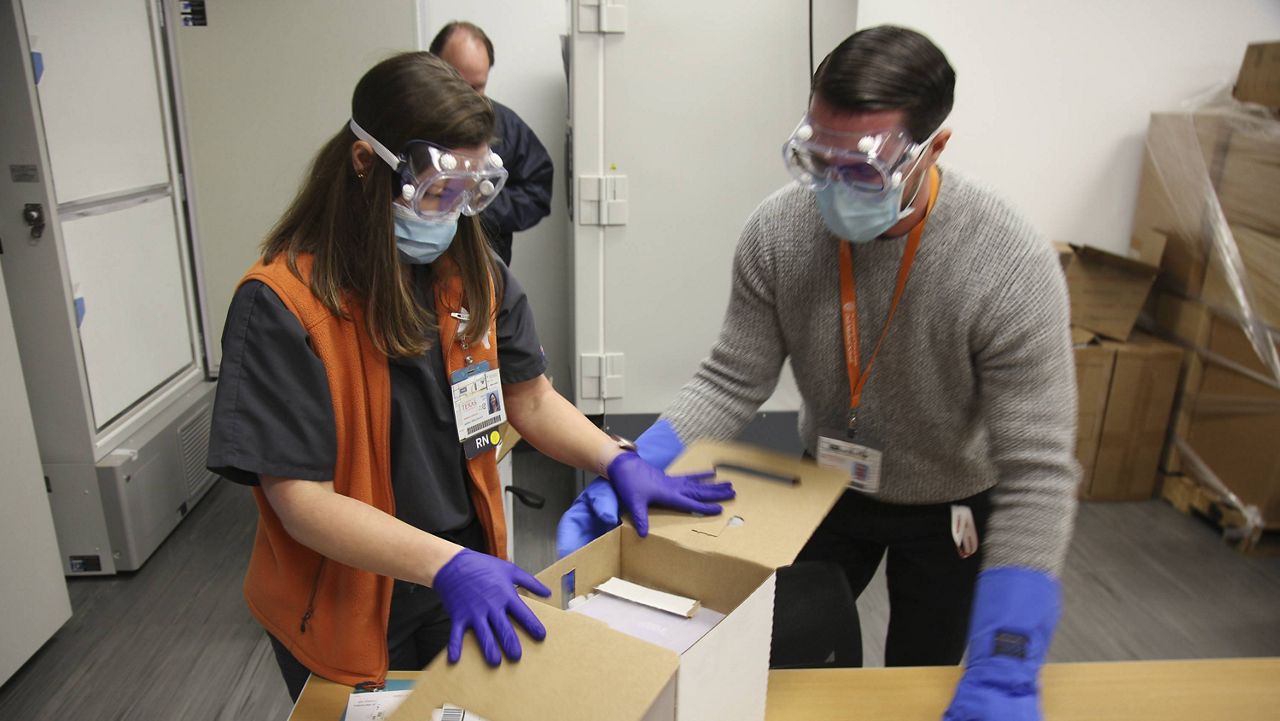 Jennifer Harrison, senior director of clinical operations at the University of Texas Health Austin Dell Medical School, and Devin Kline, materials manager open the first shipment of Pfizer-BioNTech COVID-19 vaccines to arrive at the hospital in Austin, Texas on Monday Dec.14, 2020. The facility received almost 3,000 doses and was among the first four hospitals in Texas to receive a shipment. (AP Photo/John L. Mone)