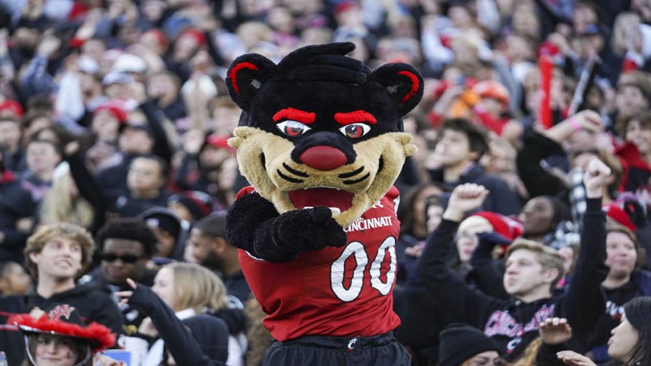 The University of Cincinnati's mascot points at the camera while surrounded by hundreds of fans at sporting event. (AP)