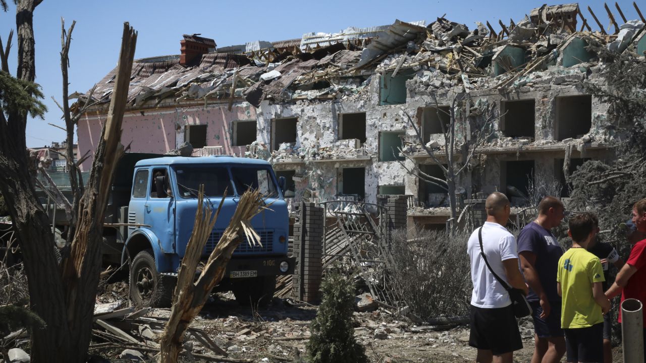 Local residents stand next to damaged residential building in the town of Serhiivka, located about 50 kilometers (31 miles) southwest of Odesa, Ukraine, Friday, July 1, 2022. (AP Photo/Nina Lyashonok)