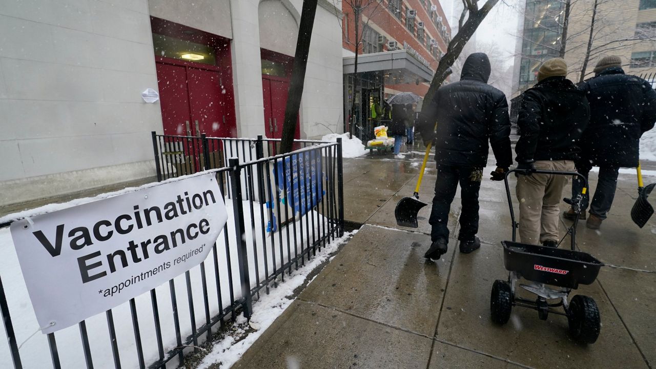 A work crew carries shovels and a cart that distributes salt after clearing a path to a vaccination site at George Westinghouse Career and Technical High School, which is being used as a vaccine hub in downtown Brooklyn. Sunday, Feb. 7, 2021, in the Brooklyn borough of New York. (AP Photo/Kathy Willens)