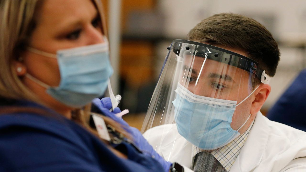 In this Dec. 14, 2020 file photo, Ohio State employee Cory Coffey, right, administers a Pfizer-BioNTech COVID-19 vaccine , in Columbus, Ohio. (AP Photo/Jay LaPrete, File)