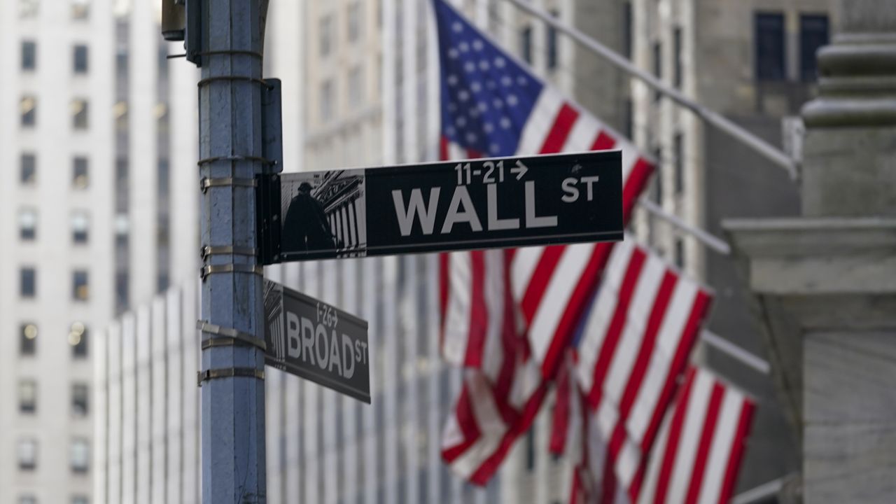 FILE: The Wall St. street sign is framed by the American flags flying outside the New York Stock exchange, Friday, Jan. 14, 2022, in the Financial District. (AP Photo/Mary Altaffer)