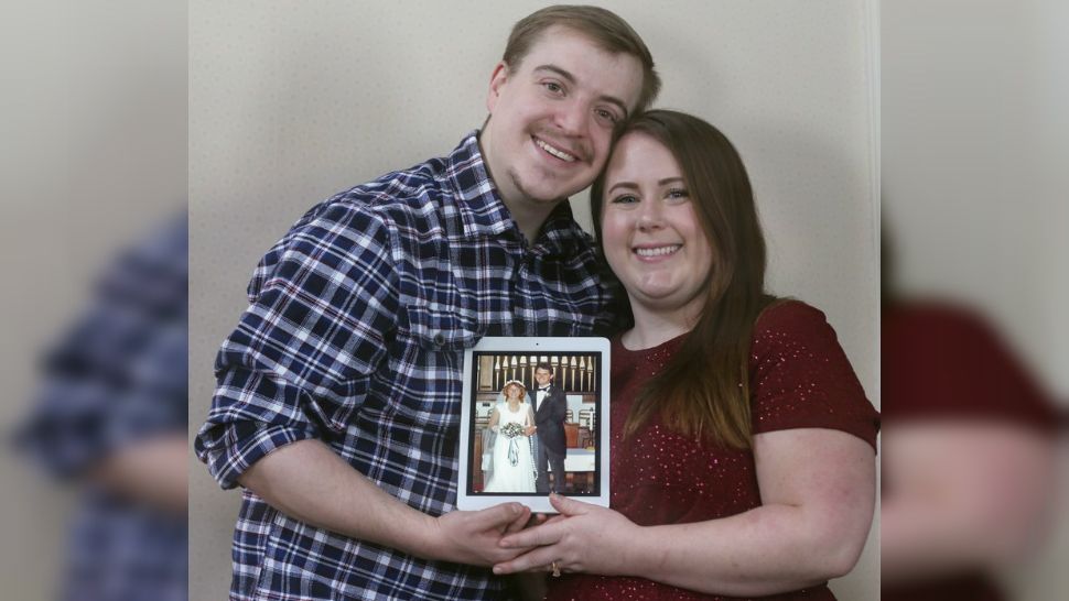 Scott Iwan and his fiance Ame Bartlebaugh hold a 1980 photo Ame’s mother in her wedding dress the day she was married. Bartlebaugh posted pictures on Facebook of a lacy wedding dress, a veil and a hoop skirt with an explanation of a1985 mix-up with the now-defunct, dry cleaner who gave her the dress, thinking it was her mothers. Bartlebaugh found the rightful owner of the dress, but is still searching for her mothers dress that she hopes to wear at her wedding in December 2019. (Phil Masturzo/Akron Beacon Journal via AP)