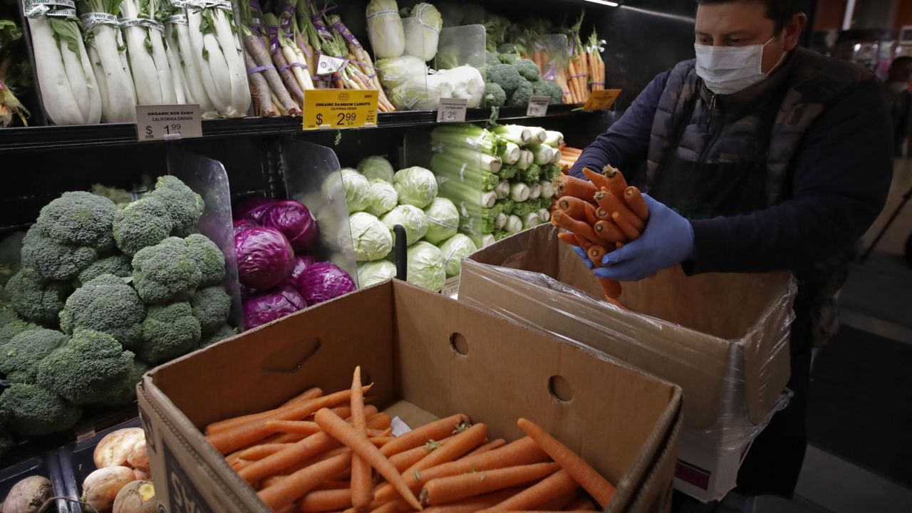 A worker stocks produce before the opening of a market in San Francisco on Friday, March 27, 2020. (AP Photo/Ben Margot, File)