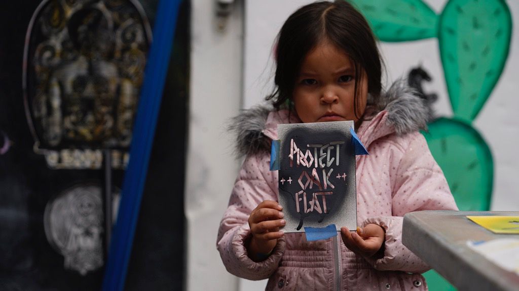 Apache Stronghold member Raetana Manny, 4, shows a sign to save Oak Flat, a site east of Phoenix that the group considers sacred, as she joined a gathering at Self Help Graphics & Art in the Los Angeles neighborhood of Boyle Heights on Monday, March 20, 2023. (AP Photo/Damian Dovarganes)