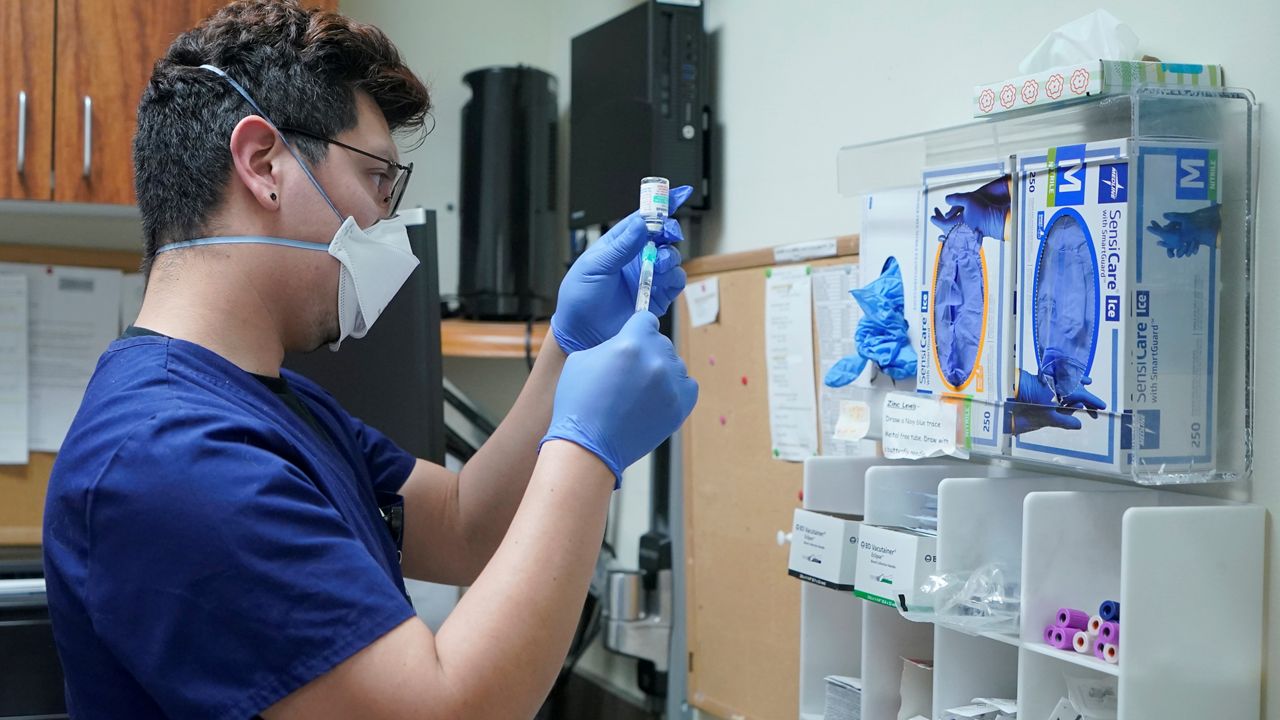 Jose Lazaro, a medical assistant at a University of Washington Medicine clinic, prepares a two-shot dose of AstraZeneca's Evusheld, the first set of antibodies grown in a lab to prevent COVID-19, Thursday, Jan. 20, 2022, in Seattle. (AP Photo/Ted S. Warren)