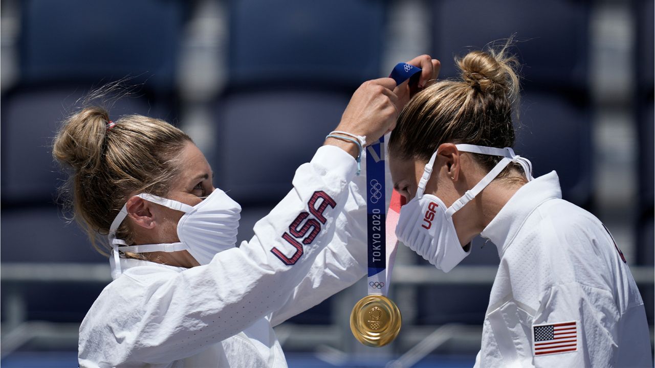 April Ross, left, of the United States, places the gold medal around the neck of teammate Alix Klineman, after winning a women's beach volleyball Gold Medal match against Australia at the 2020 Summer Olympics, Friday, Aug. 6, 2021, in Tokyo, Japan. (AP Photo/Felipe Dana)