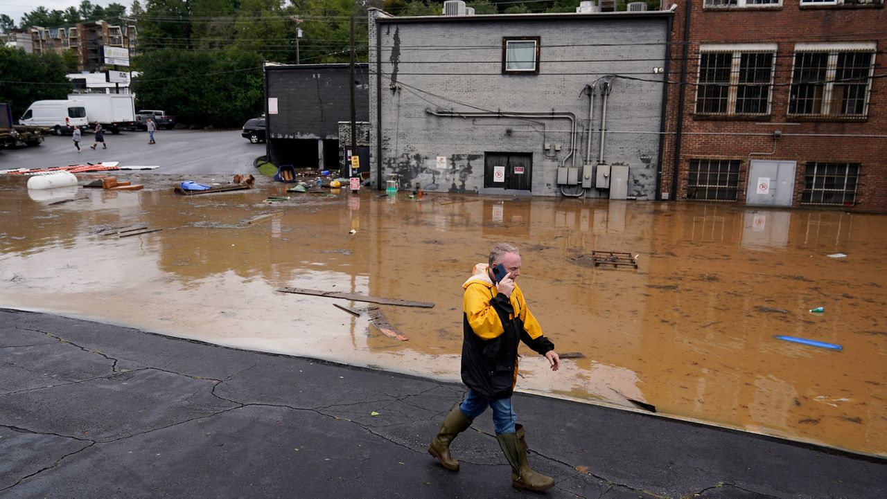 A man walks near a flooded area near the Swannanoa River on Friday, Sept. 27, 2024, in Asheville, N.C. (AP Photo/Erik Verduzco)