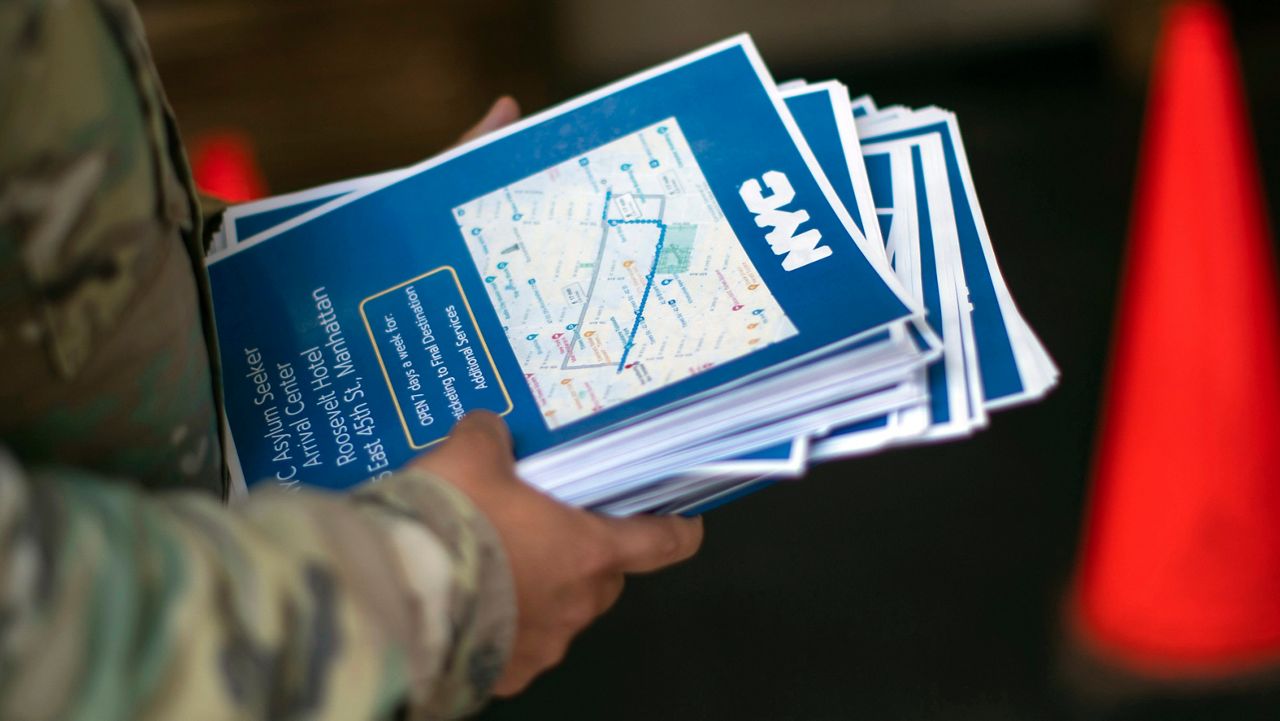 A military member carries flyers for migrants as they arrive to the Roosevelt Hotel on Friday, May 19, 2023 in New York.