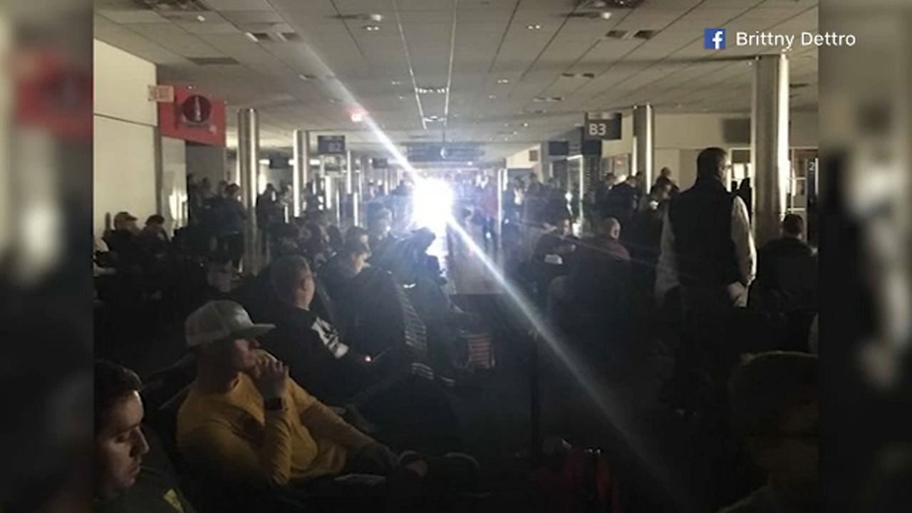 A crowd of people waiting at Hartsfield-Jackson Atlanta International Airport in the dark.