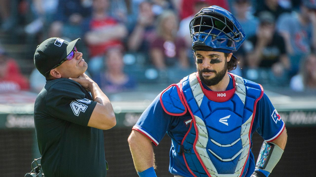 Umpire Roberto Ortiz, left, holds his neck after being hit by a foul ball by Cleveland Guardians' Ramon Laureano (not shown) as Texas Rangers' Austin Hedges, right, looks on during the fourth inning of a baseball game in Cleveland, Sept. 17, 2023. The Guardians are reuniting with Hedges, agreeing with the veteran catcher on a one-year, $4 million contract, a person familiar with the deal told The Associated Press, Sunday, Dec. 10, 2023. (AP Photo/Phil Long, File)