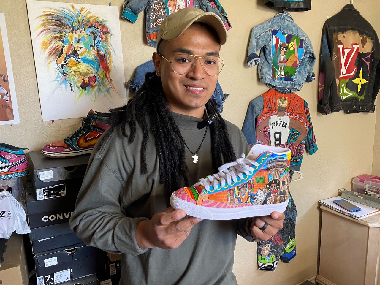 Dimas Anthony Martinez poses with a pair of sneakers that he created. (Spectrum News 1/Lauren Kendrick)