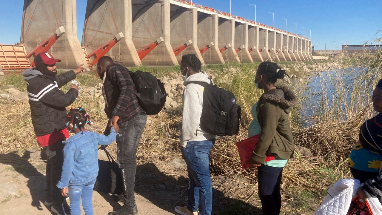 A Mexican smuggler guides a Haitian family across the Morelos Dam over the Colorado River from Los Algodones, Mexico, on Feb. 4, 2022, to Yuma, Ariz., on the other side. (AP Photo/Elliot Spagat, File)