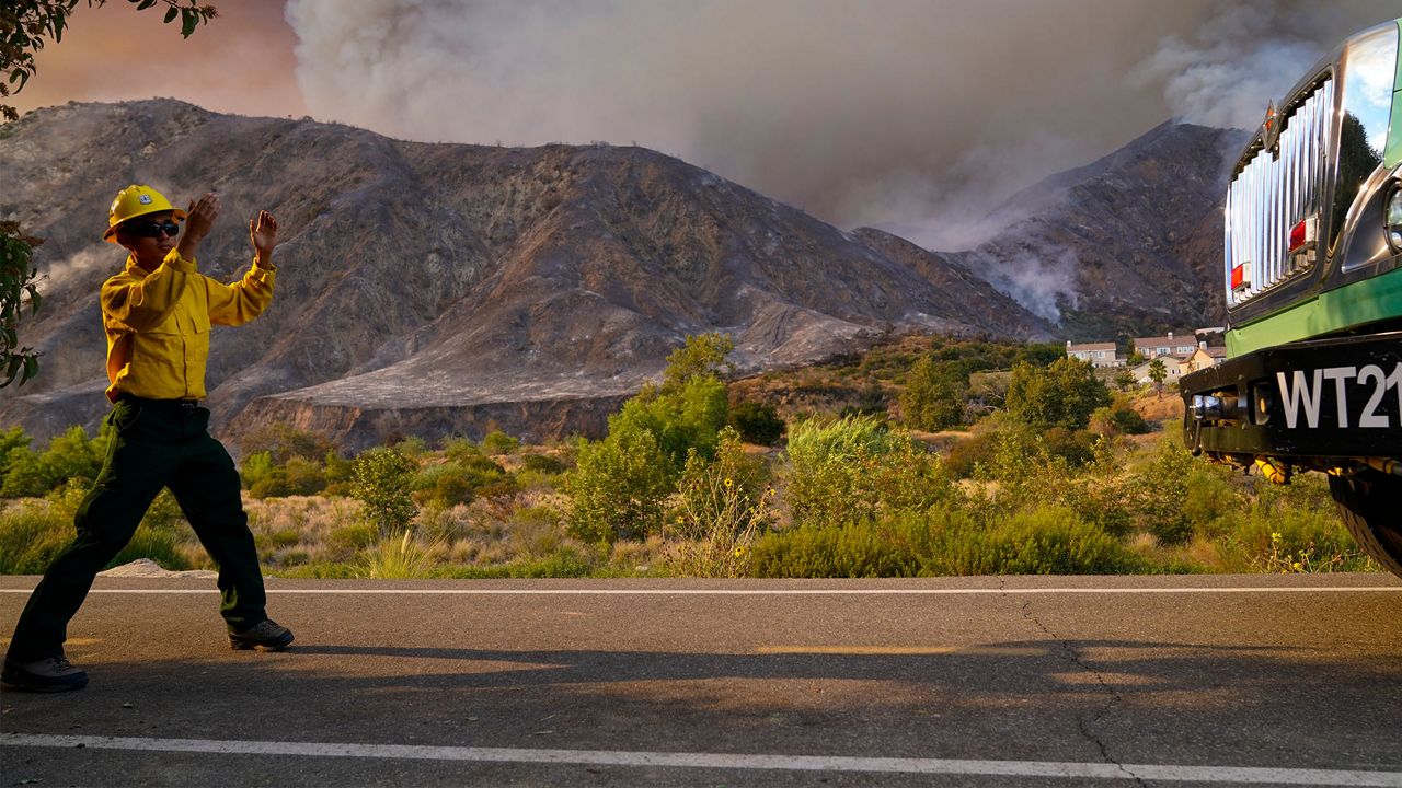 A firefighter directs a truck in front of the Ranch Fire, Thursday, Aug. 13, 2020, in Azusa, Calif. (AP Photo/Marcio Jose Sanchez)