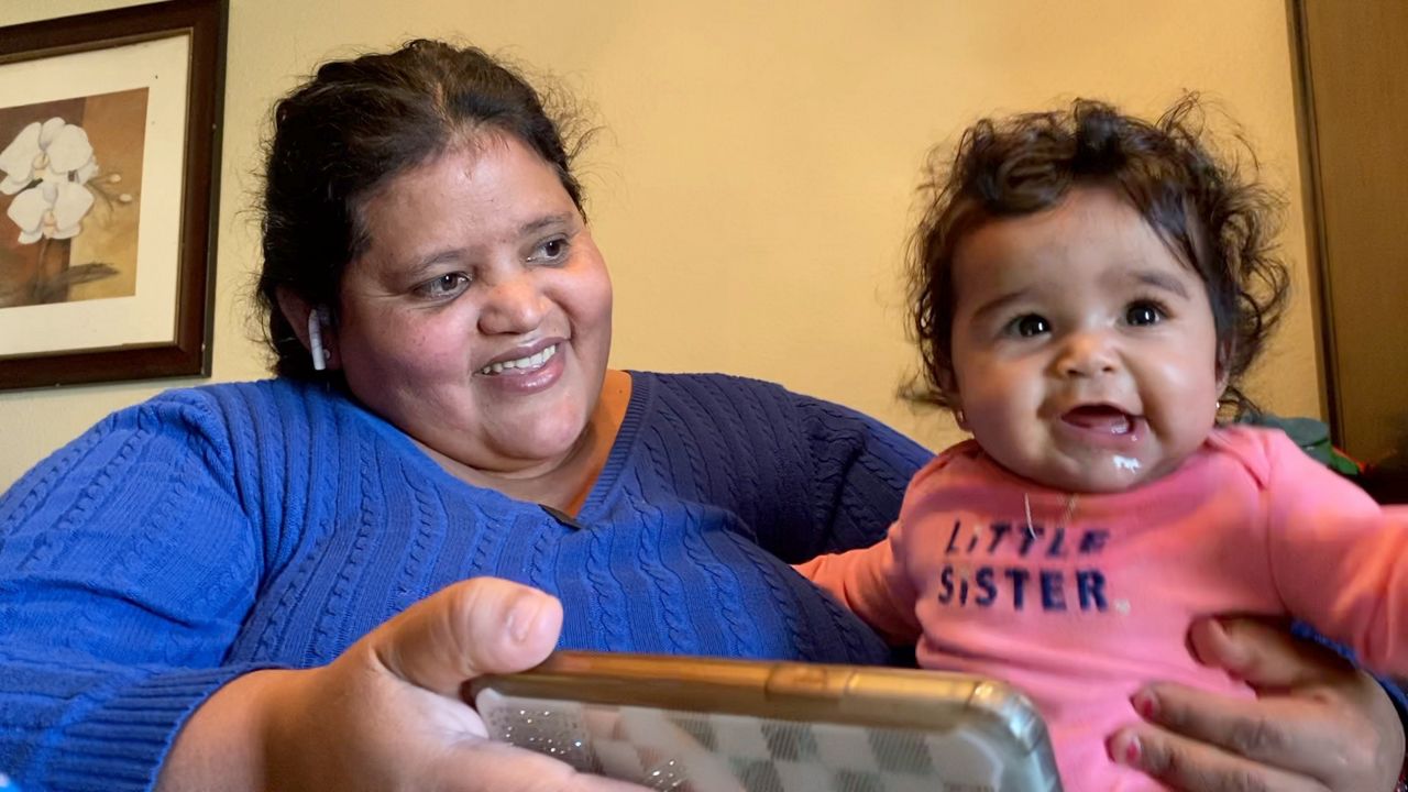 Wendy Figueroa and daughter Alexa Figueroa watch baby nursery rhyme videos on a cell phone. (Lupe Zapata/Spectrum News 1)