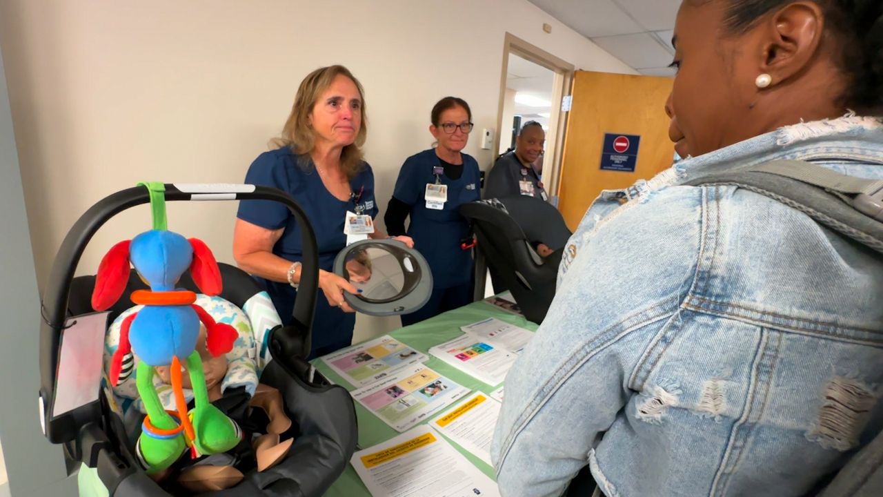 TGH staff shows a local mom how to properly install a child car seat. (Spectrum Bay News 9/Saundra Weathers)