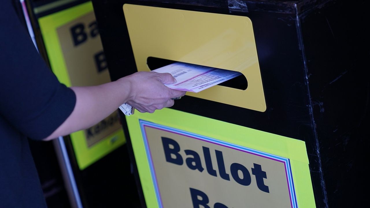 A person places ballots in a drop box at the Clark County Election Department, Oct. 29, 2020, in Las Vegas. 