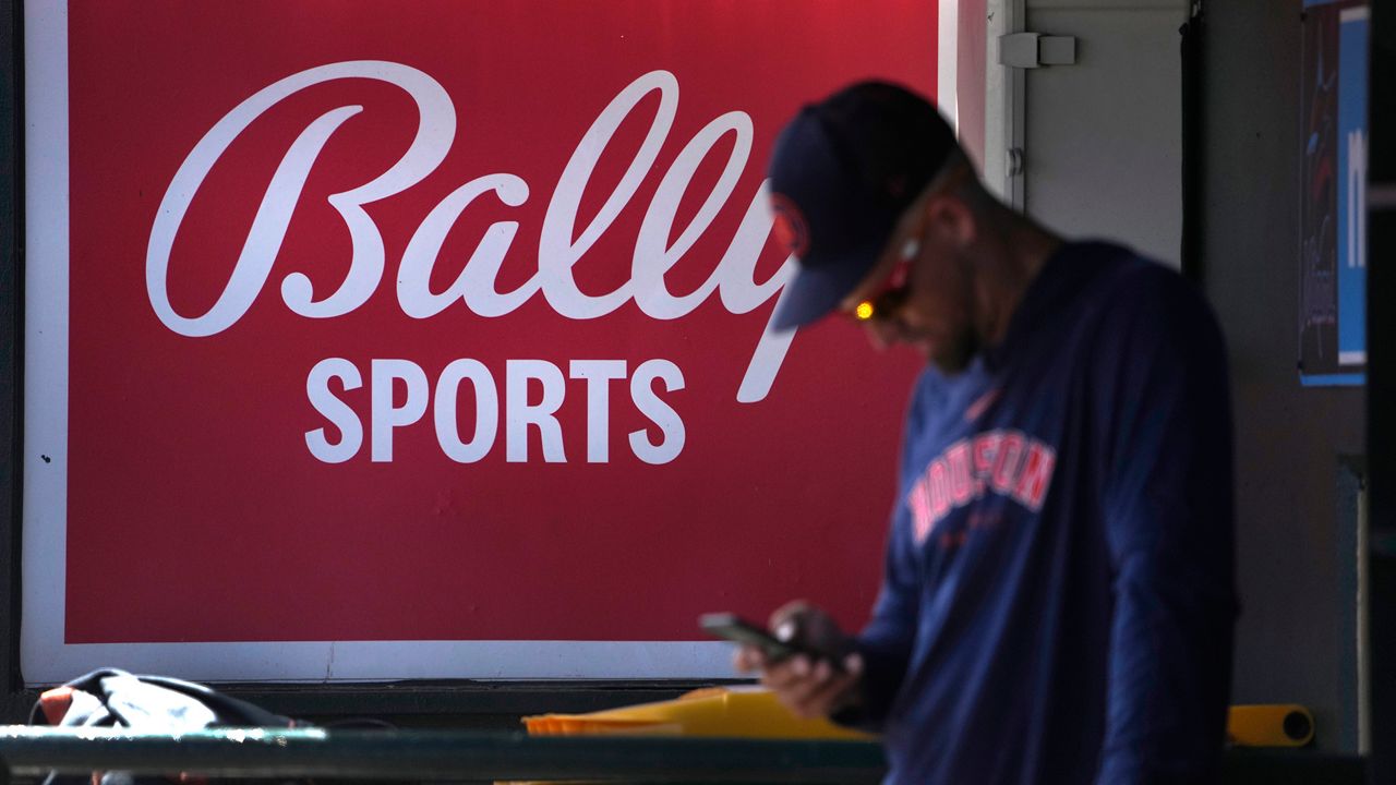 A member of the Houston Astros stands in the dugout in front of a Bally Sports sign before the team's spring training baseball game against the St. Louis Cardinals