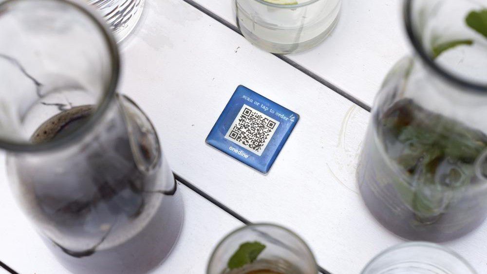 Drinks surround a barcode attached to the table at Bartaco, that patrons use to order and pay at the restaurant in Arlington, Va., on Thursday, Sept. 2, 2021. The restaurant uses an automated app for ordering and payments. Instead of servers Bartaco uses "food runners" to bring the orders to the tables. (AP Photo/Jacquelyn Martin)