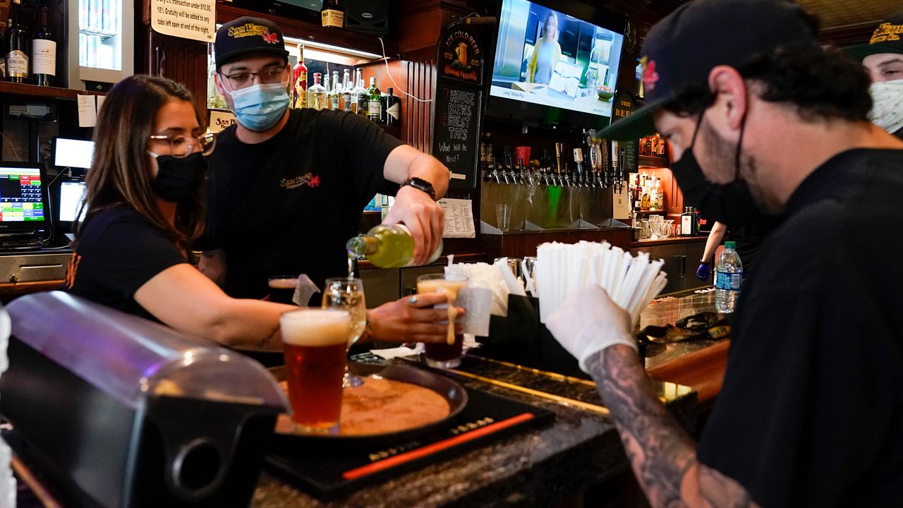 Jessica Ciaramitaro, Daryn Feenstra and Nicholas Soriano mix drinks while wearing face masks at the bar at San Pedro Brewing Company on Friday, May 29, 2020, in the San Pedro area of Los Angeles. Restaurants were allowed to open their dining rooms with restrictions today. (AP Photo/Ashley Landis)