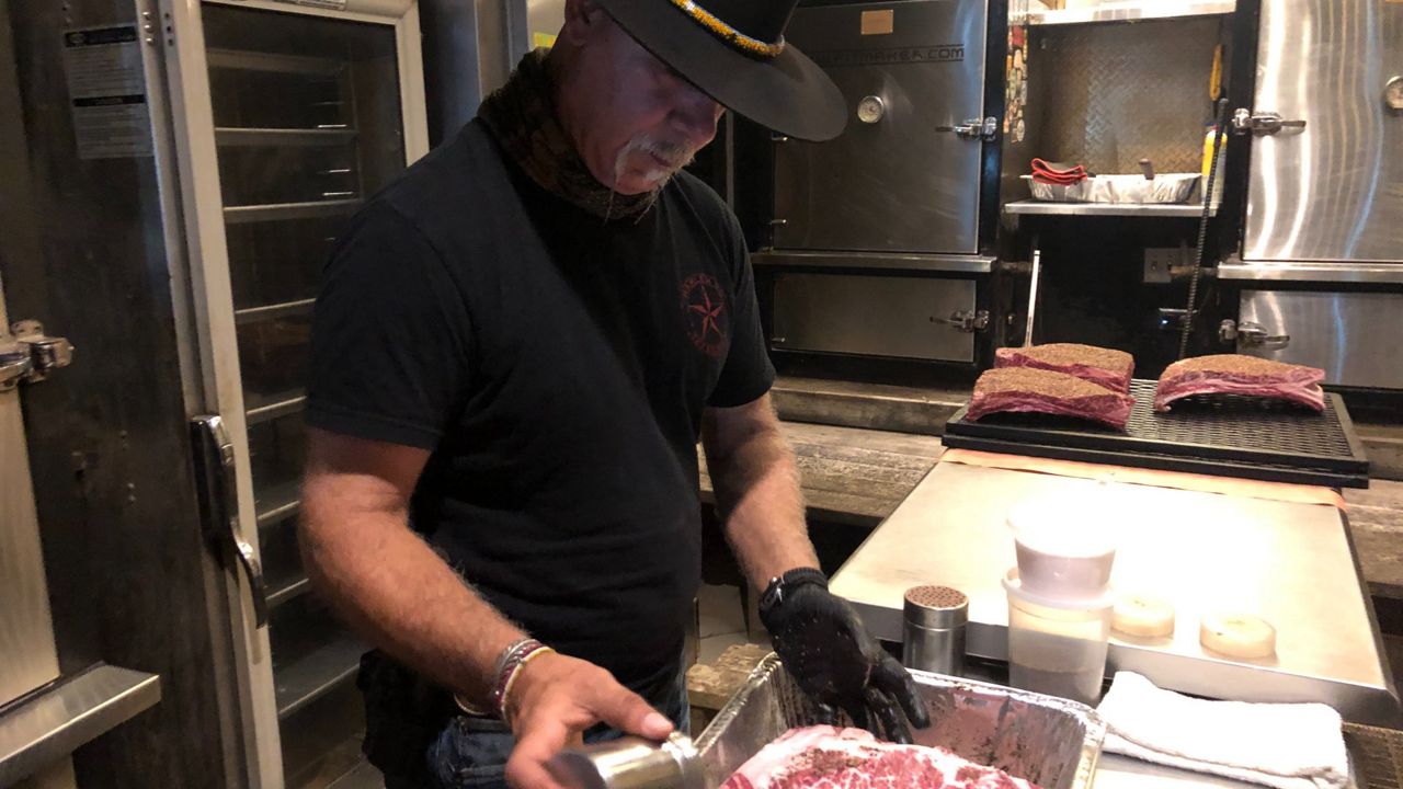 Ara Malekian seasons meat at Harlem Road Texas Barbecue. (Bryan Boes/Spectrum News)